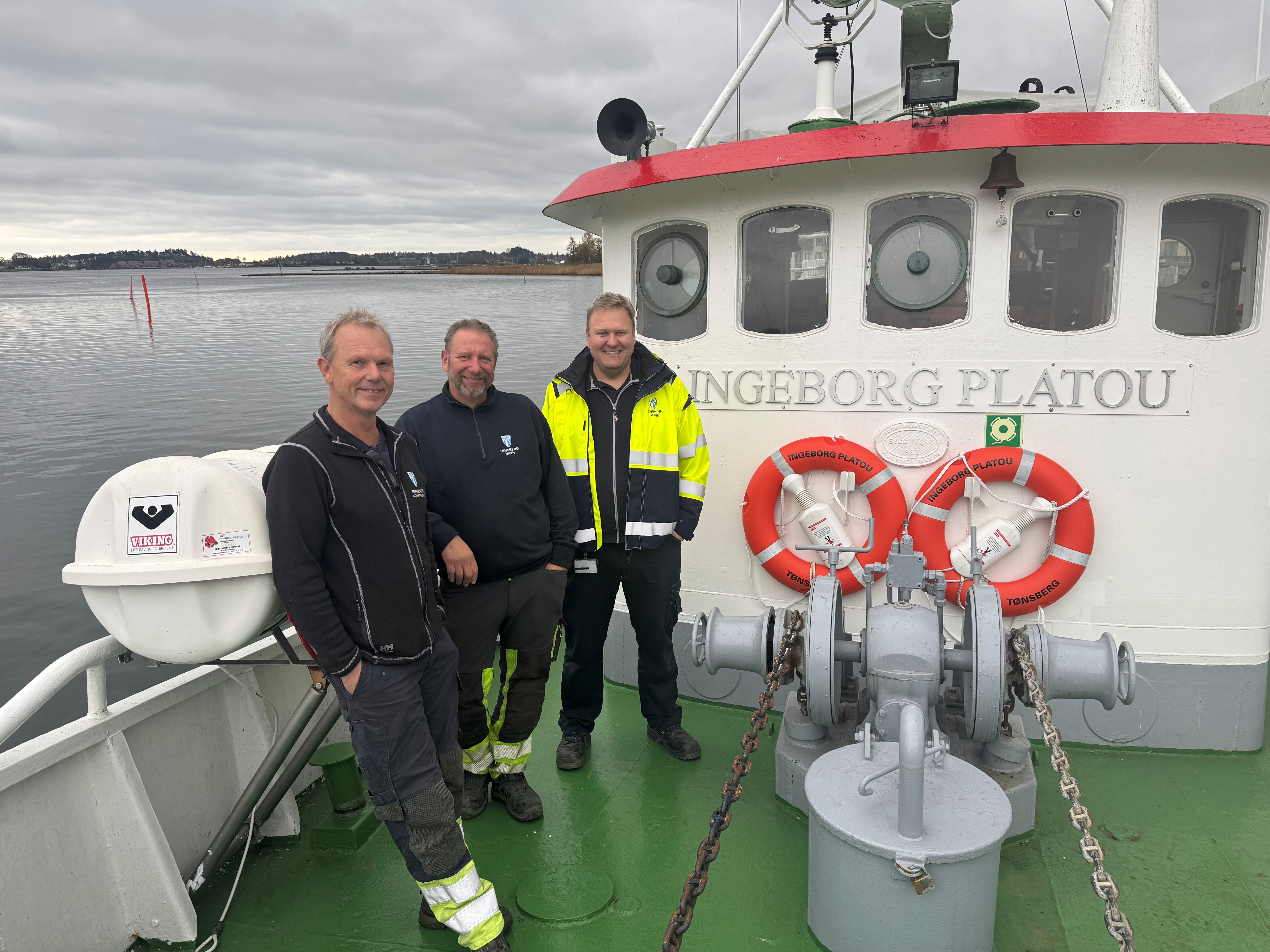 Tre menn på dekket til en båt. 