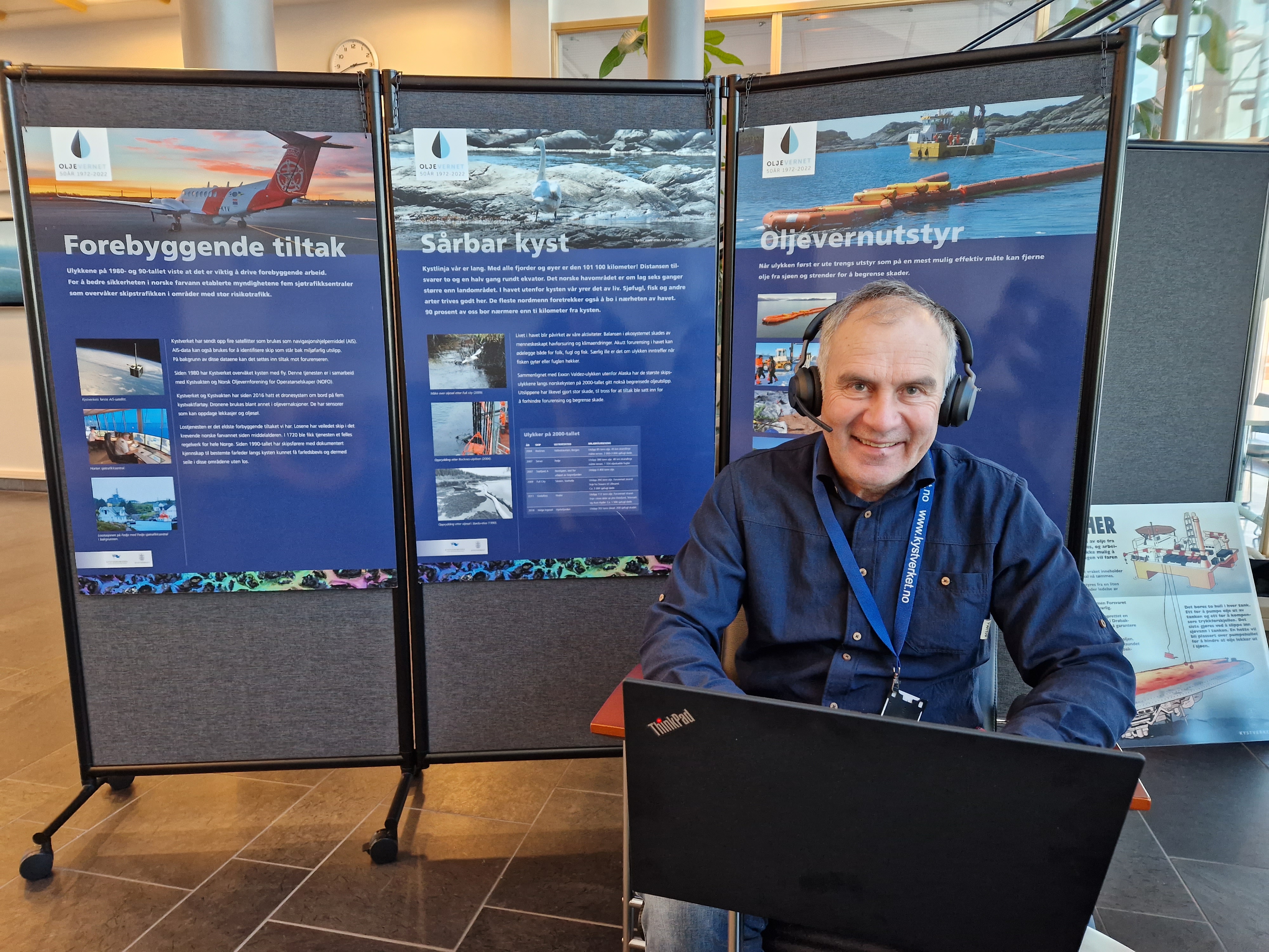 Ole Christian Bjerkemo med hodetelefoner foran plakater om oljevern